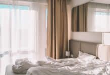 white bed linen near white window curtain