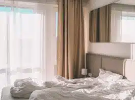 white bed linen near white window curtain